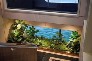 A view of a balcony with a potted plant arrangement and a glimpse of the sea.