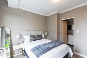 A bedroom with a bed, bedside tables, a mirror, and a door leading to a bathroom.
