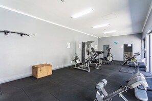 A gym with exercise equipment, a wooden box, and a door leading to another room.