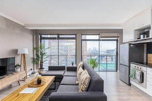 A modern apartment with a living room, dining area, and kitchen.