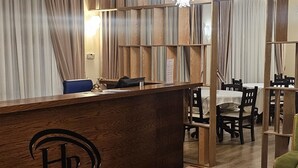 A hotel reception area with a wooden reception desk, a red carpet, a green sofa, and a chandelier. - Broadway Boutique Hotel (Tirana)