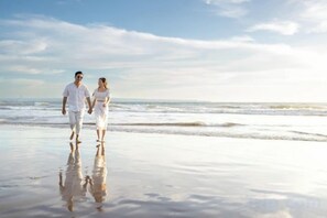 A couple walking on a beach with the ocean in the background. - Vinna Villa Seminyak by The Wina Resorts (Bali)