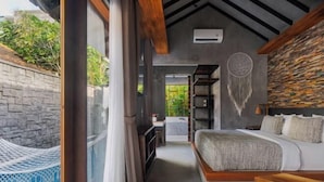A modern bedroom with a bed, a vanity, and a dreamcatcher on the wall. - Vinna Villa Seminyak by The Wina Resorts (Bali)