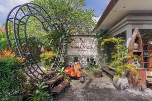 A garden entrance with a sign for Vinna Villa, a scooter, and a bench. - Vinna Villa Seminyak by The Wina Resorts (Bali)