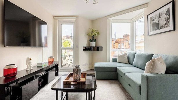 Ein modernes Wohnzimmer mit einem großen Flachbildfernseher, einem grünen Sofa, einem Couchtisch und einer schwarzen TV-Konsole.