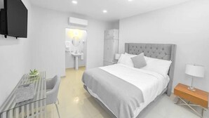 A modern hotel room with a large bed, a desk, and a chair. - Studio+Desk+QueenBed in Tijua Near USborder (Tijuana)