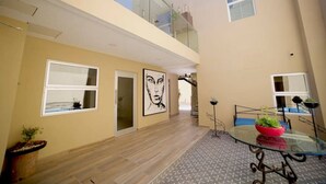 Un interior moderno con una mesa de vidrio, plantas en macetas y obras de arte en las paredes.