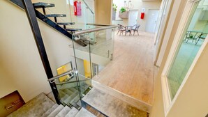 A modern interior with a glass staircase leading to a dining area. - Studio/Desk/Private in TJ Near US border (Tijuana)