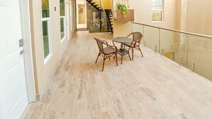 A spacious hallway with a wooden floor, a glass railing, and a table with chairs. - Studio/PrivateBalcony in TJ near USBorder (Tijuana)