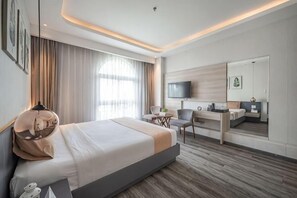 Et moderne hotelværelse med en stor seng, et skrivebord, en stol, et fjernsyn og et spejl.