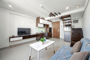 A modern living room with a flat-screen TV, a dining table, and a sofa. - Cozrum Homes - Sonata Residence (Ho Chi Minh City)