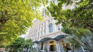 A multi-story hotel with a classic architectural style, featuring a central entrance with a covered walkway and a fountain. - Cozrum Homes - Sonata Residence (Ho Chi Minh City)