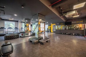 A gym with exercise equipment, a reception desk, and a glass partition. - Cozrum Homes - Sonata Residence (Ho Chi Minh City)
