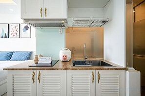 Une cuisine de taille réduite avec des meubles blancs, un plan de travail et un évier.