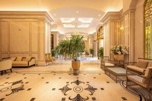 A hotel lobby with a marble floor, sofas, a large potted plant, and a chandelier. - Cozrum Homes - Sonata Residence (Ho Chi Minh City)