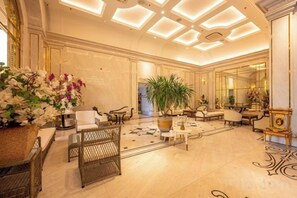 Un hall d’entrée spacieux avec un plafond haut, une grande plante en pot et un mobilier élégant.