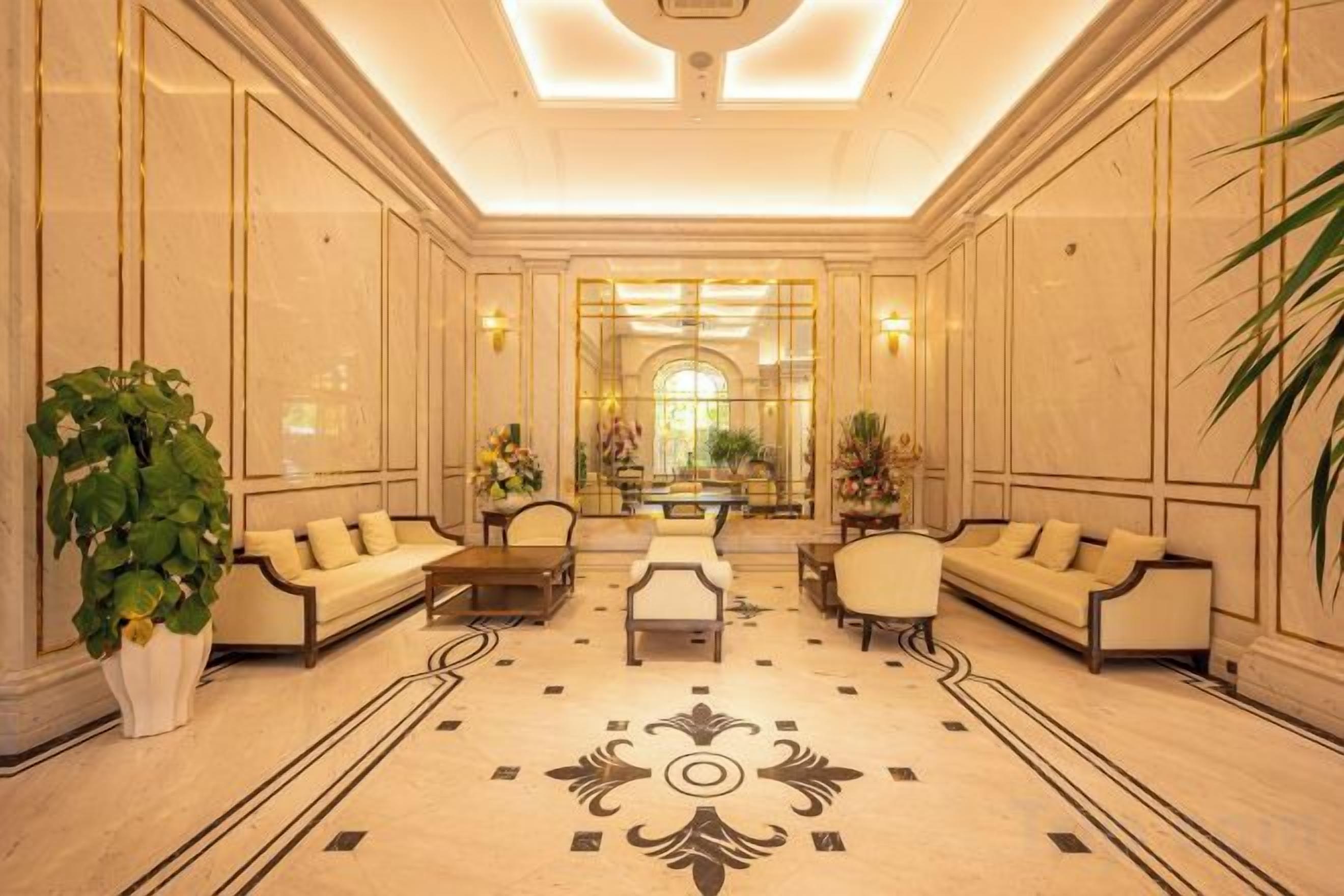 Un hall d’entrée spacieux avec un espace salon central, un grand miroir et un motif décoratif sur le sol.