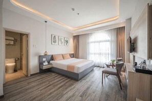 A modern hotel room with a large bed, bedside table, and a small desk area. - Cozrum Homes - Sonata Residence (Ho Chi Minh City)