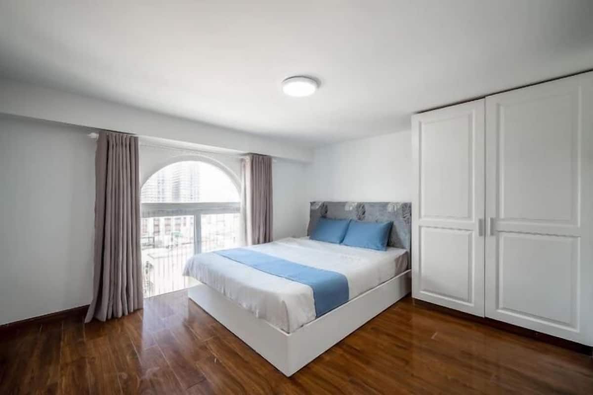 Ein Schlafzimmer mit Bett, Kleiderschrank und einem fenster mit Vorhängen.