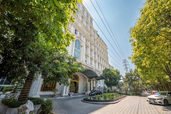 A hotel with a paved driveway, a covered entrance, and a car parked on the street. - Cozrum Homes - Sonata Residence (Ho Chi Minh City)