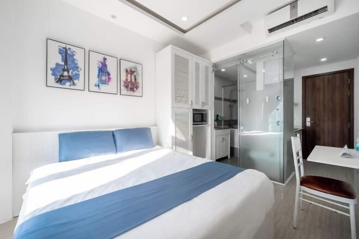 Ein modernes Hotelzimmer mit einem großen Bett, einem Schreibtisch und einer Duschkabine aus Glas.