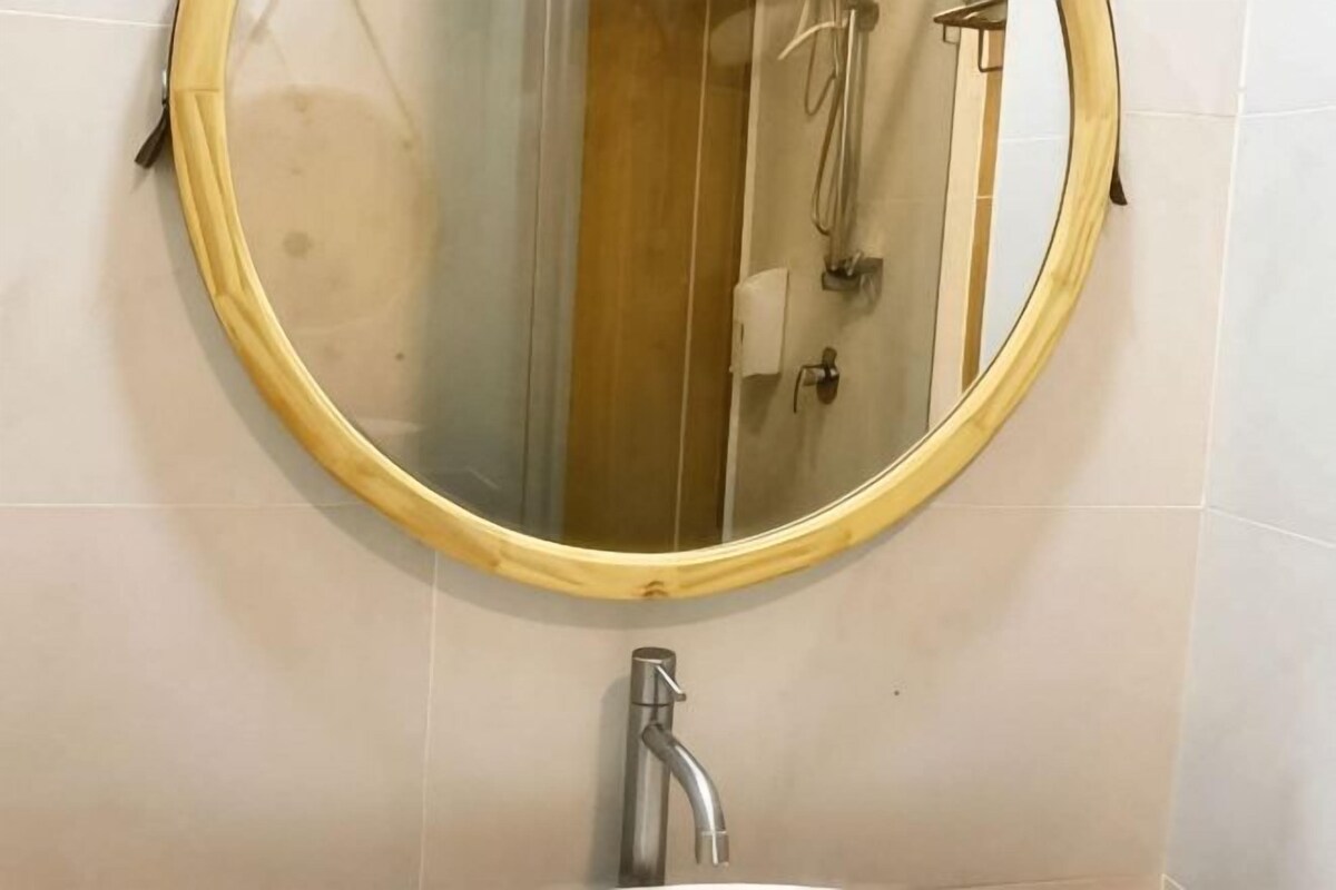 Un baño con un espejo redondo, un lavabo y una ducha.