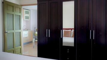 Un dormitorio con cama, armario y baño visible a través de una puerta abierta.