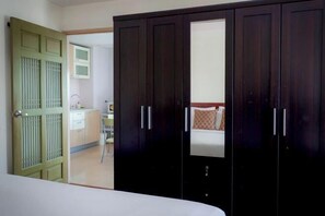 A bedroom with a bed, a wardrobe, and a bathroom visible through an open door.