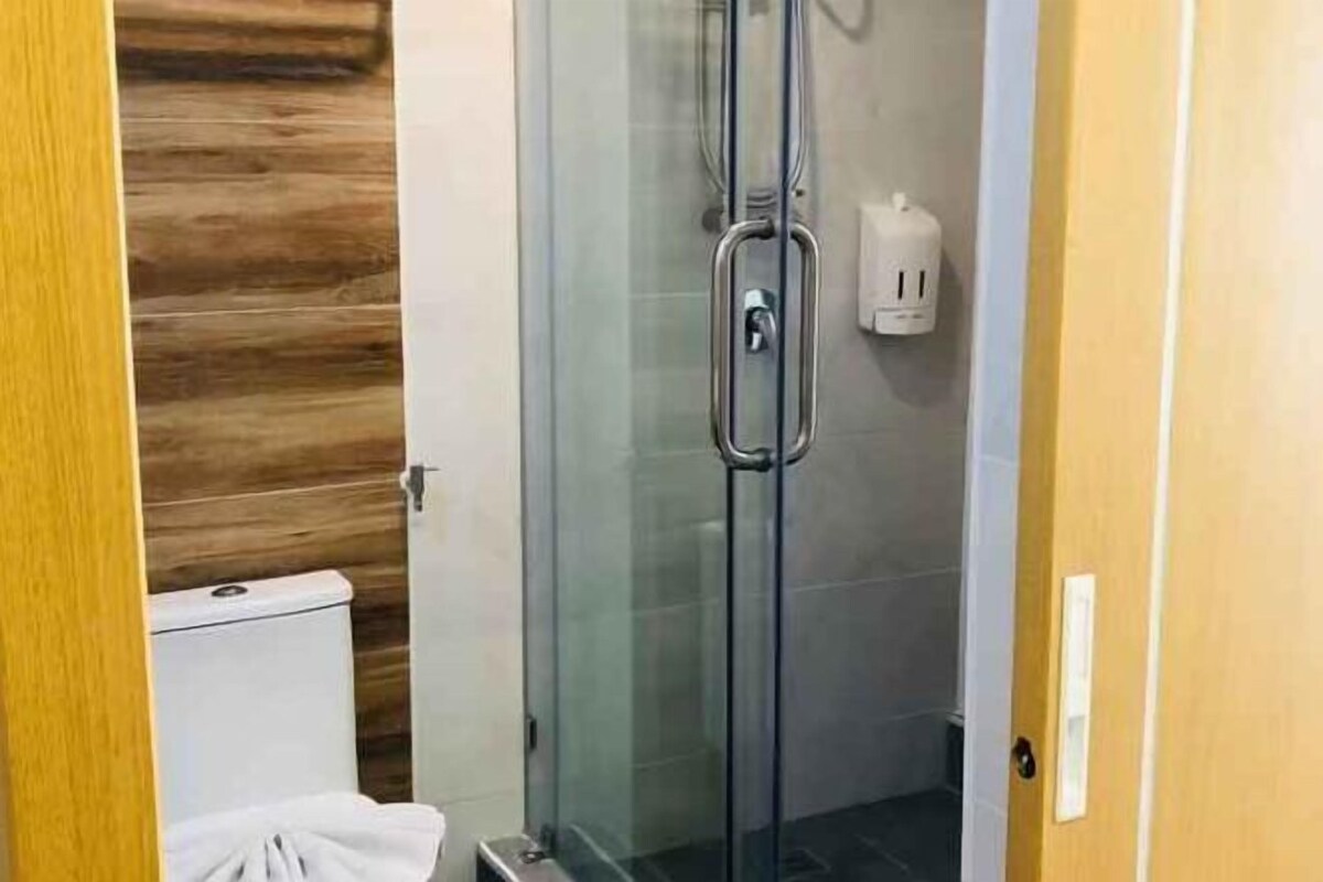 Eine gläserne Duschkabine mit Toilette und Handtuchspender.