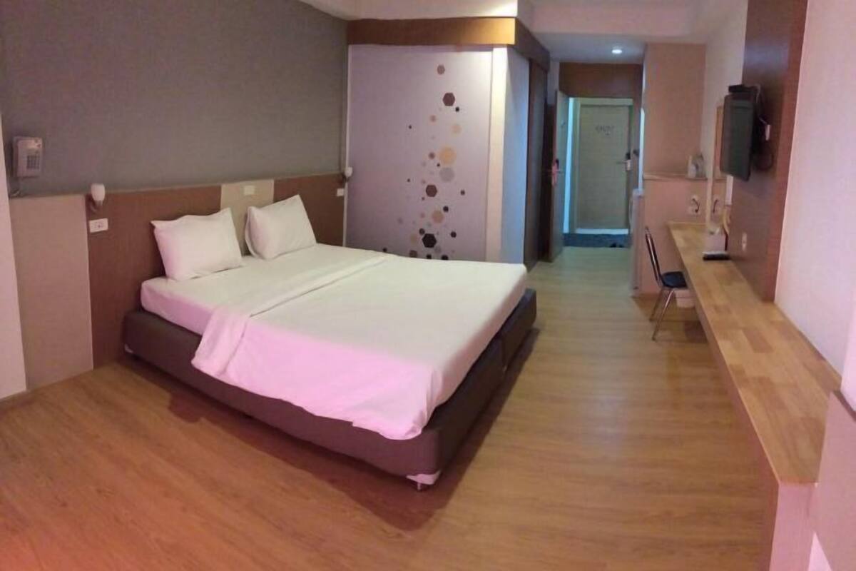 A hotel room with a large bed, a desk, and a television.
