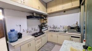 Cozinha com armários bege, fogão a gás, micro-ondas e pia.