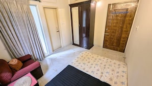 Quarto com cama, guarda-roupa, cadeira e janela com cortinas.