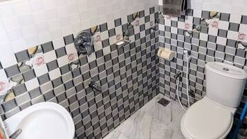 A bathroom with a white sink, toilet, and shower area. The walls are tiled with a checkered pattern, and the floor is marble.