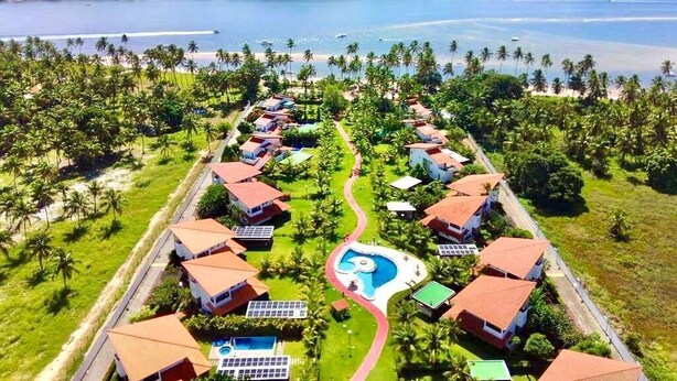 A resort with multiple bungalow-style buildings, a central swimming pool, and a view of the surrounding ocean and greenery. - CLUB MERIDIONAL CARNEIROS (Tamandaré)