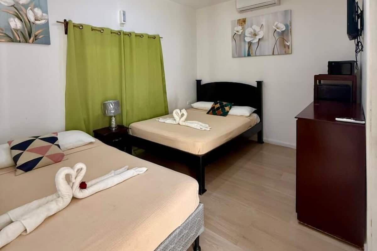Una habitación de hotel con dos camas, un escritorio, un televisor y obras de arte en las paredes.