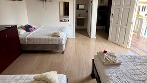 Une chambre d’hôtel avec deux lits, une télévision, un tableau et une salle de bain visible à travers une porte ouverte.