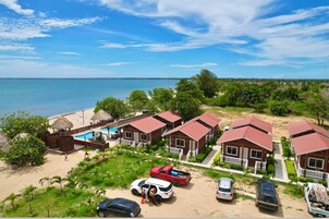 Un resort frente al mar con varias cabañas de madera, una piscina y una zona de playa.