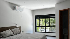 Une chambre moderne avec un grand lit, une fenêtre et un appareil de climatisation.
