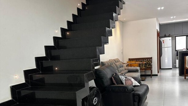 Un intérieur moderne avec un escalier noir menant à un espace de vie.