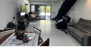 Un salon moderne avec un escalier, un coin repas et une vue à travers des portes vitrées.