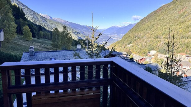 A wooden deck with a view of a valley and mountains.