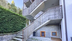 A multi-story building with a stone facade, a wooden staircase, and a small window with a wooden frame.