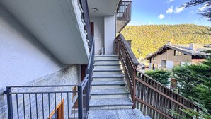 A staircase leading to a balcony with a view of a forested hillside.
