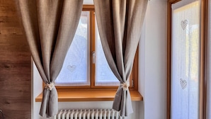 A room with two windows, each with a curtain tied at the bottom.