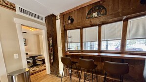 Un espace bar avec un sol en bois, une poubelle et des tabourets de bar.