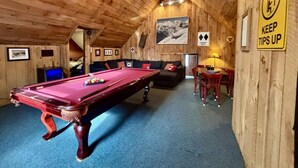 Un intérieur en bois comprenant une table de billard, un canapé et un coin repas.