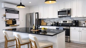 A modern kitchen with white cabinets, stainless steel appliances, and a central island with bar stools.