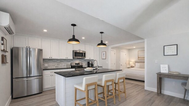 A modern kitchen with a central island, stainless steel appliances, and pendant lighting.