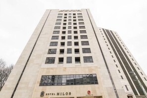 A tall hotel building with a modern architectural design, featuring a prominent entrance with a sign. - Uiwang Milos Hotel (Uiwang-si)