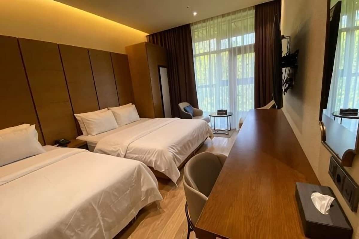Een hotelkamer met twee bedden, een houten bureau, een stoel, een bijzettafeltje en een spiegel.